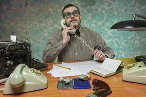 empregado com óculos falando ao telefone no escritório