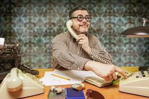 empregado com óculos falando ao telefone no escritório