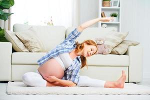 mulher grávida praticando ioga e fitness em casa