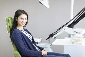 menina sorridente na cadeira odontológica foto
