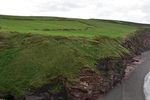 belo campo de grama verde no topo das falésias no mar da Irlanda foto