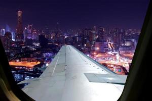 voo noturno no céu crepuscular, vista incrível do avião da janela. assento na janela do avião com vista para a cidade à noite. foto