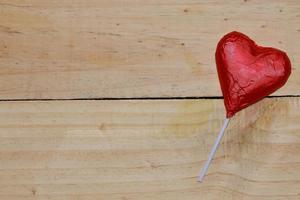 coração de chocolate envolto em vermelho na madeira. conceito de dia dos namorados. espaço para texto. foto