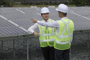 dois engenheiros asiáticos em uma estação de painel solar foto