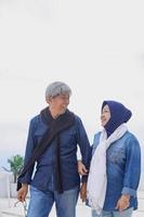 close-up de casal romântico sênior em estilo casual está caminhando juntos enquanto fala e sorri contra o céu azul. conceito de estilo de vida de casal de idosos. foto