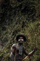 retrato do homem da tribo dani vestindo koteka, roupas tradicionais de papua. homens da tribo dani olhando ao redor e prontos para caçar presas animais na beira do rio. foto