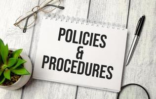 texto de políticas e procedimentos no bloco de notas com óculos, caneta e calculadora foto