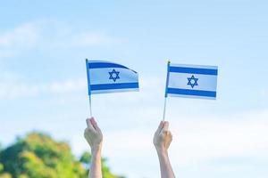 mão segurando a bandeira de israel no fundo da natureza. dia da independência de israel e conceitos de celebração feliz foto