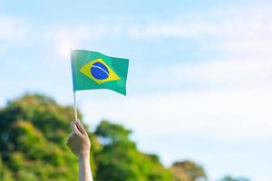 mão segurando a bandeira do brasil sobre fundo de céu azul. dia da independência de setembro e conceitos de celebração feliz foto