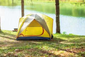 acampar sob a floresta, barraca amarela perto do lago. conceito de viagens, viagens e férias ao ar livre foto