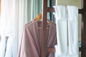 closeup roupão de banho limpo e toalha pendurada no guarda-roupa de madeira no hotel de luxo. relaxar e viajar conceito foto