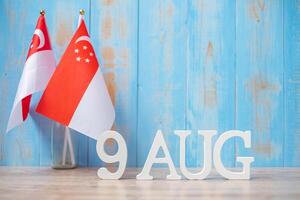 texto de madeira de 9 de agosto com bandeiras em miniatura de singapura. dia da independência de cingapura, dia nacional da cidade-estado e conceitos de república de celebração feliz foto