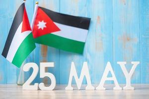 texto de madeira de 25 de maio com bandeiras da Jordânia. dia da independência da jordânia e conceitos de celebração feliz foto