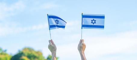 mão segurando a bandeira de israel no fundo da natureza. dia da independência de israel e conceitos de celebração feliz foto