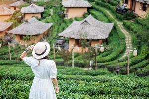 mulher de turista feliz no vestido branco desfrutar de belo chá garden.traveler visitando na vila tailandesa de ban rak, mae hong son, tailândia. conceito de viagens, férias e férias foto