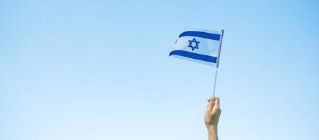 mão segurando a bandeira de israel no fundo da natureza. dia da independência de israel e conceitos de celebração feliz foto
