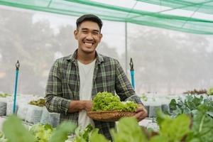 jardineiro masculino colheu legumes frescos na fazenda. agricultor asiático na fazenda orgânica vegetal. conceito de fazenda orgânica de hidroponia. foto