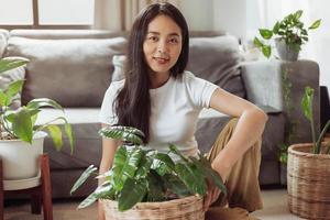 mulher feliz sentada com suas plantas em casa. mulher asiática jardinagem em casa, jardinagem em casa. foto