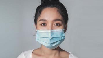 mulher asiática usa máscara médica protegendo da pandemia de coronavírus. close-up da mulher asiática usa máscara médica cirúrgica. foto