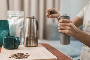 jovem mulher fazendo café com equipamentos em casa. mulher feliz usando moedor de café manual para fazer café em casa foto