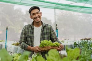 jardineiro masculino colheu legumes frescos na fazenda. agricultor asiático na fazenda orgânica vegetal. conceito de fazenda orgânica de hidroponia. foto