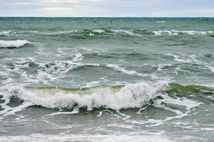 mar azul com ondas espumantes e céu nublado, marinha foto