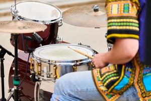 homem baterista tocando bateria percussão com baquetas, kit de bateria no palco do concerto, baquetas e bateria foto