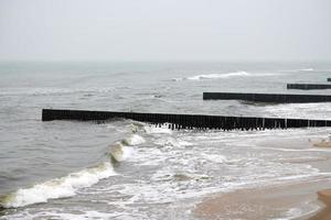 velhos quebra-mares de madeira nas ondas do mar, paisagem de inverno foto