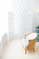 lindo quarto interior limpo brilhante clássico branco de luxo em estilo barroco com grande janela, poltrona e composição de flores. foto