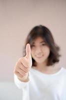 mulher sorridente feliz de Ásia com polegares para cima gesto