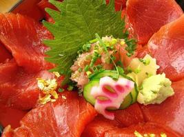 close-up cor vibrante de fatias de atum vermelho frescor no sashimi de arroz japonês don com pepino gengibre e wasabi foto