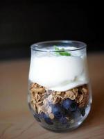 vidro de close-up de vista lateral de camadas de granola de mirtilos e topo de iogurte grego com hortelã foto