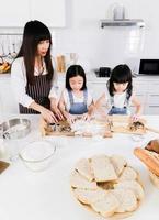 mãe de família feliz e filha de dois filhos fazem um bolo na cozinha foto