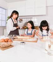 mãe closeup lendo um livro e criança se diverte cozinhando assando na cozinha foto