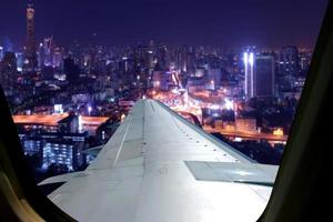 voo noturno no céu crepuscular, vista incrível do avião da janela. assento na janela do avião com vista para a cidade à noite. foto