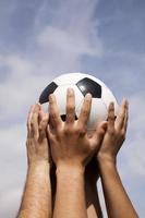 mãos segurando uma bola de futebol no ar foto