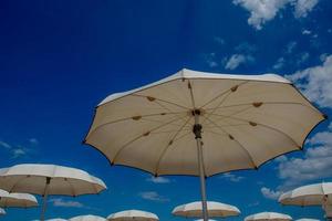 guarda-chuvas brancos abertos na praia foto