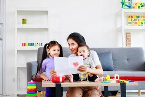 filha fofa envia cartões de mãe de amor para a mãe e beija enquanto cuida do bebê, conceito de dia das mães foto