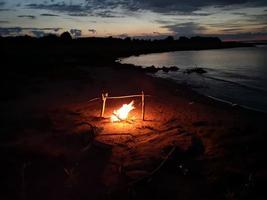 a fogueira queima à noite na margem do lago foto