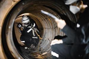 inspeção masculina de dois trabalhadores mediu a espessura circular do tubo da bobina da espessura mínima da varredura da caldeira foto