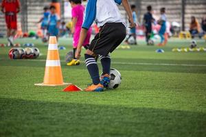 táticas de bola de futebol de meninos no campo de grama com cone foto