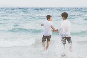 retrato homossexual jovem casal asiático correndo com alegre juntos na praia no verão, ásia gay indo turismo para lazer e relaxar com felicidade em férias no mar, conceito legal lgbt. foto