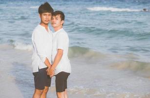 retrato homossexual jovem casal asiático juntos na praia no verão, ásia gay de mãos dadas indo mar para lazer e relaxar com romântico e feliz em férias no mar, lgbt com conceito legal. foto