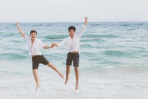 retrato homossexual jovem casal asiático correndo e pulando com alegres juntos na praia no verão, ásia gay indo turismo para lazer e relaxe com felicidade em férias no mar, conceito legal lgbt. foto