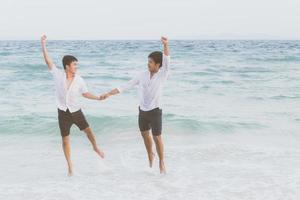 retrato homossexual jovem casal asiático correndo e pulando com alegres juntos na praia no verão, ásia gay indo turismo para lazer e relaxe com felicidade em férias no mar, conceito legal lgbt. foto
