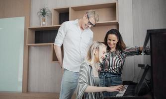 família feliz, mãe, pai e filha tocando piano em casa, conceito para relacionamento familiar. foto