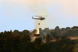 um helicóptero da ONU apaga um incêndio em uma floresta na fronteira israel-líbano. foto