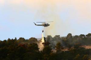 um helicóptero da ONU apaga um incêndio em uma floresta na fronteira israel-líbano. foto