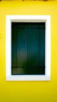 janela de pintura de madeira verde em burano com parede amarela brilhante foto