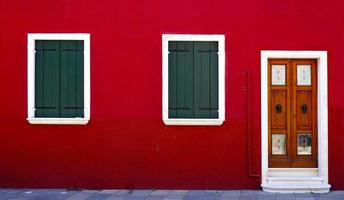 porta de madeira e duas janelas na parede vermelha foto